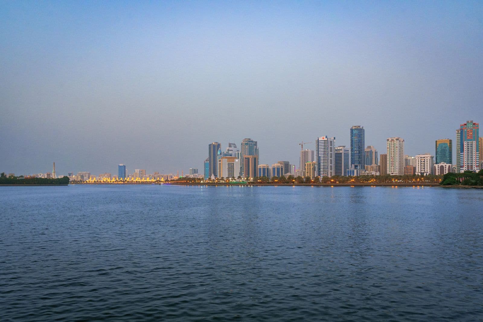 The Sharjah skyline reflected on water at dusk